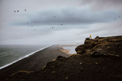 Man at cliff against sky