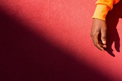 Close-up of hand against red wall