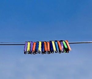 Low angle view of cloth clips against blue sky