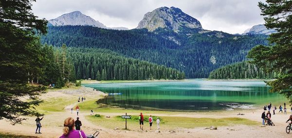 People by lake against mountains