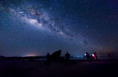 People standing on field against sky at night
