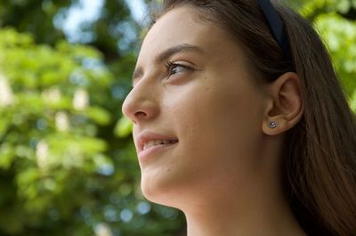 Close-up of thoughtful young woman looking away against trees