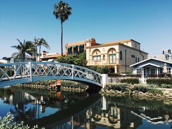 Arch bridge over river by buildings against clear sky