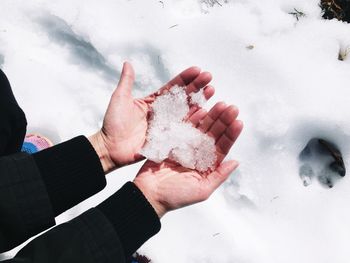 High angle view of human hands holding snow in heart shape during winter