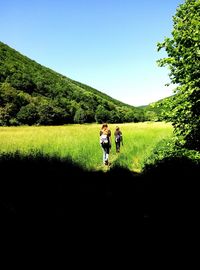 People walking on field against clear sky