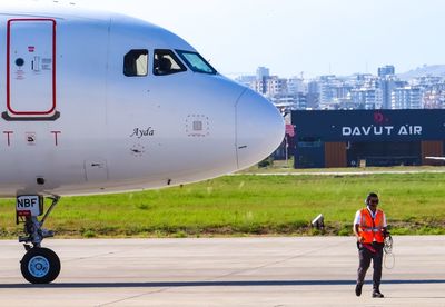 Man standing on airplane at airport runway