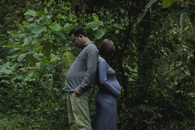 Side view of couple standing against trees