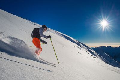 Man skiing on snowcapped mountain against sky