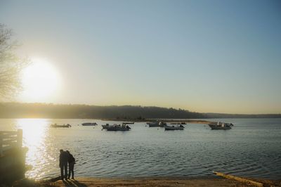 Silhouette woman standing in sea against clear sky during sunset