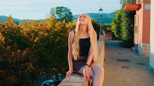 Portrait of young woman sitting on street