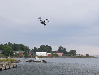 Airplane flying over river against sky