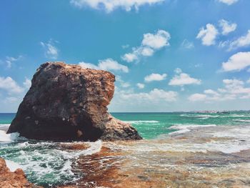 Rock formation on beach against sky