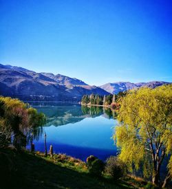 Scenic view of lake and mountains against clear blue sky