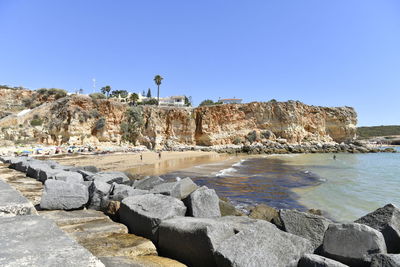 Rocks on beach against clear blue sky