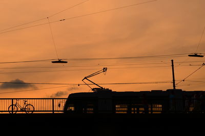 Low angle view of train moving on bridge against sunset sky