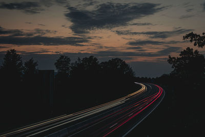 Light trails on road against sky at night