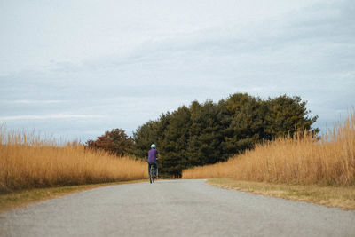 Rear view of man walking on road against sky