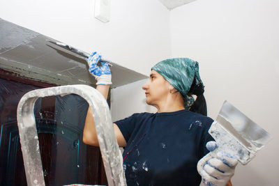 Woman plastering wall in home