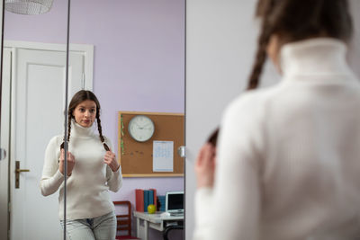 Fashion girl tunes up in front of the mirror and makes different faces.