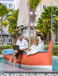 Side view of woman using mobile phone while sitting in boat