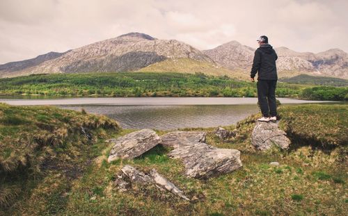 Landscape scenery, man standing on the rock with mountains at lough inagh in connemara national park