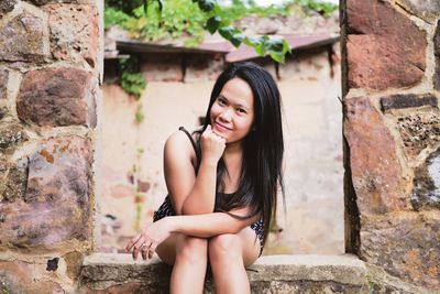 Portrait of smiling woman sitting on old window sill