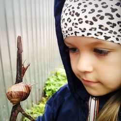 Close-up of cute girl holding snail on stick