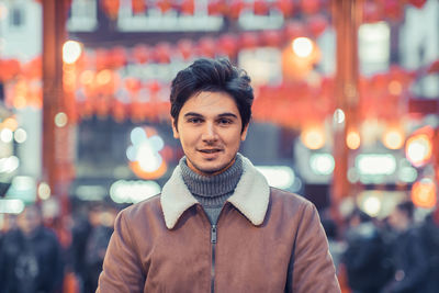 Portrait of smiling man standing in city at night