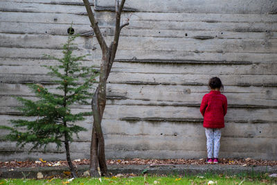 Rear view of woman standing against wall