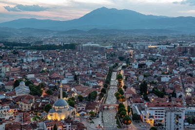 Aerial view of cityscape by mountain at dusk