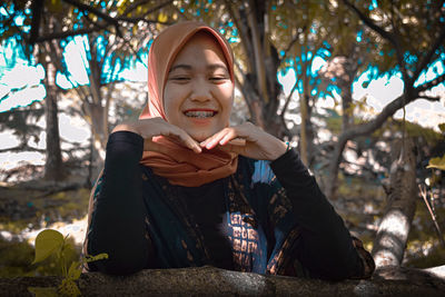 Portrait of smiling young woman sitting on tree