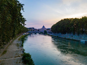 View of river passing through city at sunset