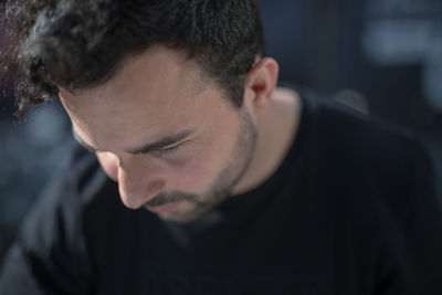 Close-up of thoughtful young man looking down while sitting indoors