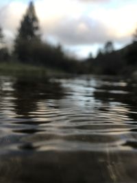 Surface level of lake against cloudy sky