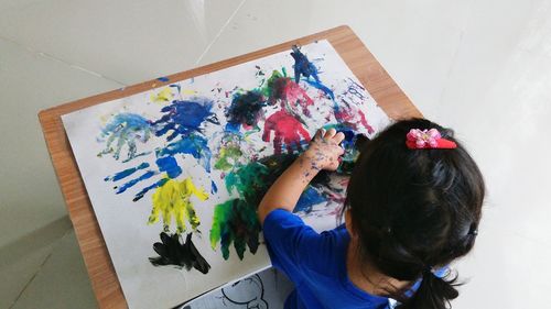 High angle view of girl painting on paper at home