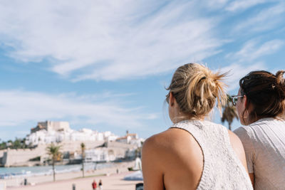 Rear view of woman against sky in city