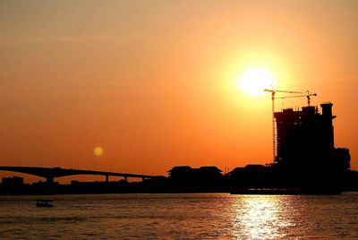 Silhouette bridge over sea against sky during sunset