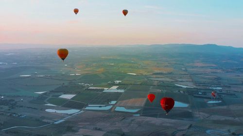 Hot air balloons flying over landscape against sky