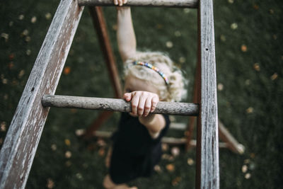 High angle view of girl hanging on monkey bars at playground