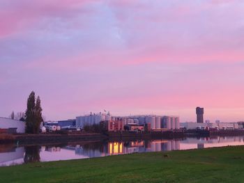 River by buildings against sky at sunset