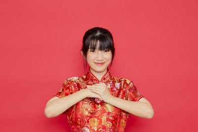 Portrait of a smiling young woman against red background