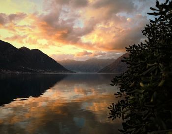 Scenic view of lake by mountains against orange sky