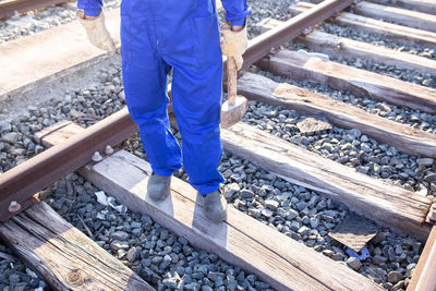 Low section of man in uniform holding hammer standing on railroad track