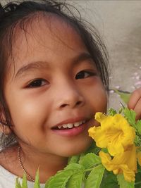 Close-up portrait of smiling girl with yellow flower