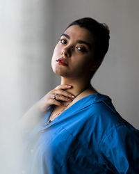 Portrait of young woman standing against wall