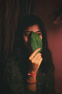 Close-up of woman holding leaf at home