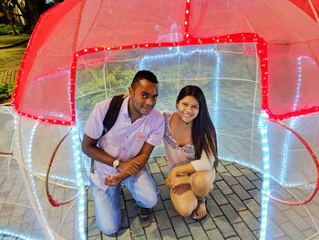 Portrait of smiling young woman with red umbrella in city