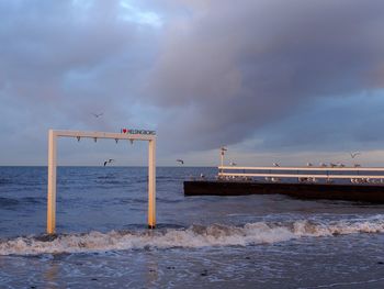 Pier on beach against sky