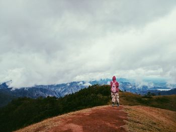 Rear view of person walking on mountain against sky