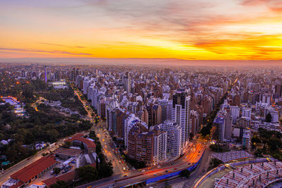 High angle view of illuminated street amidst buildings against sky during sunset